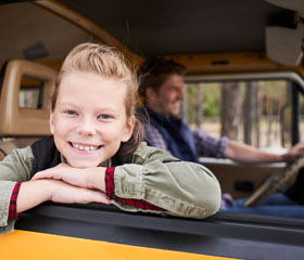 Niña sonriendo en el asiendo delantero de un coche