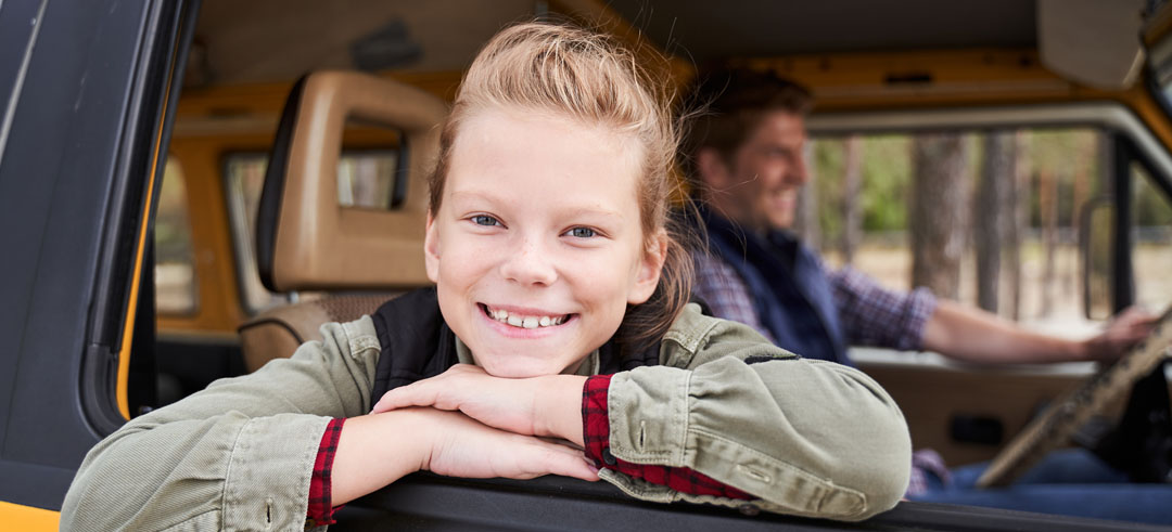 Niña sonriendo en el asiendo delantero de un coche