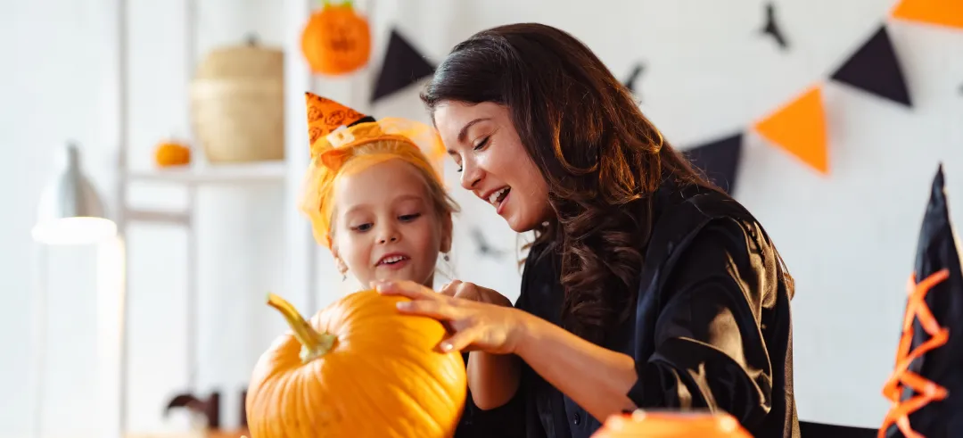 Madre e hija decorando una cabaza de Halloween en su casa