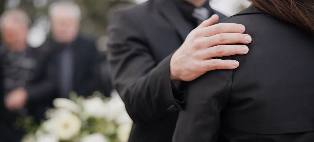 Una persona apoyando a otra en un funeral