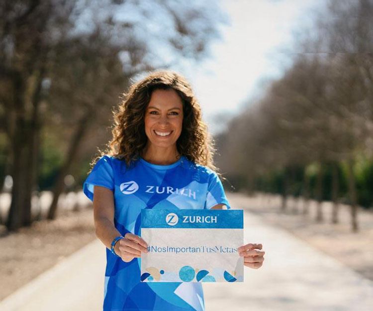 chica con camiseta de deporte Zurich, sujetando un dorsal con el slogan: #Nos Importan Tus Metas