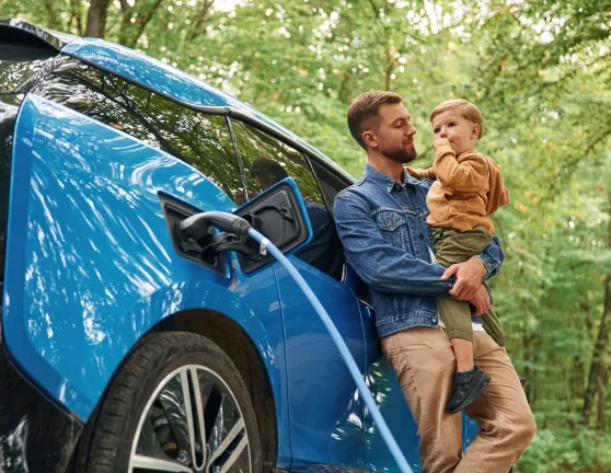Padre e hijo junto a un coche eléctrico cargando