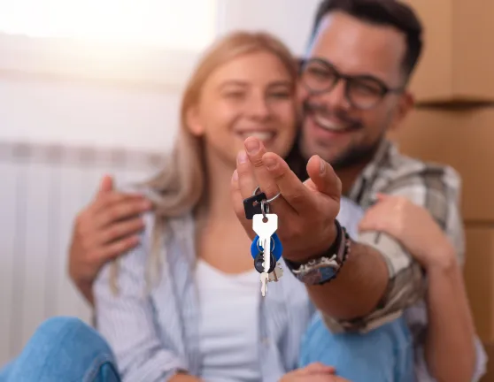 Pareja abrazada con una llaves de una casa en la mano
