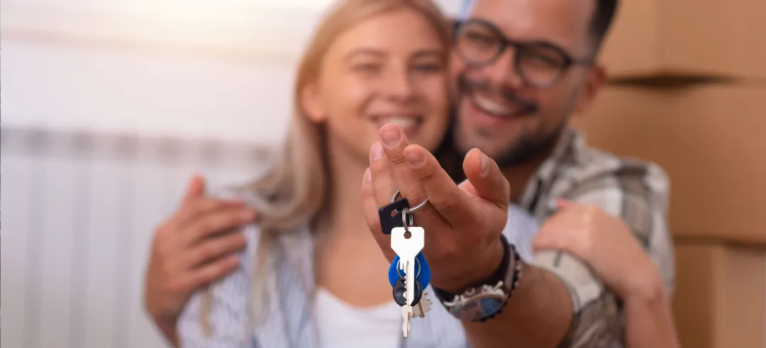 Pareja abrazada con una llaves de una casa en la mano