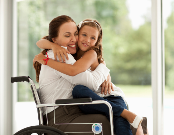 Niña abrazando a persona en silla de ruedas