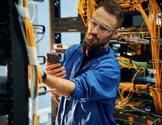 Técnico trabajando en la gestión de cables de servidores en un centro de datos.