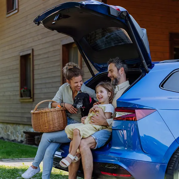 familia feliz sentada en el maletero del coche