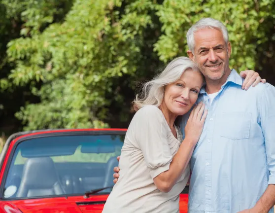 Expats couple with a car in the background.