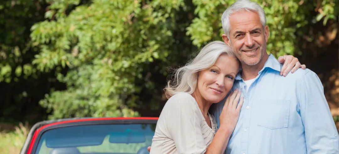 Expats couple with a car in the background.