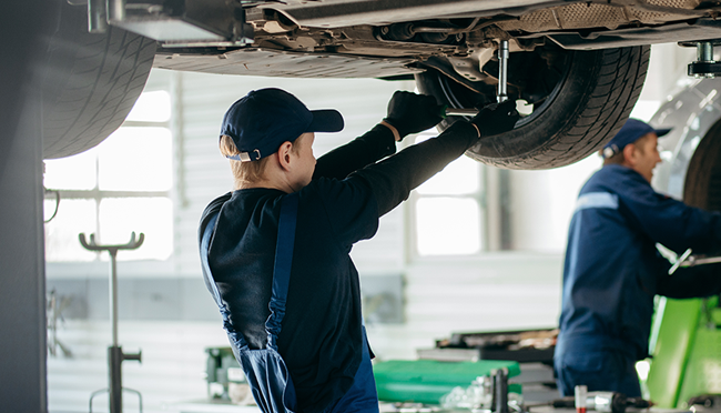 mecánico en un taller revisando los bajos de un coche