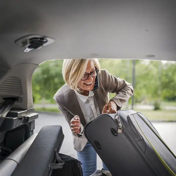 mujer madura sacando un maleta del coche