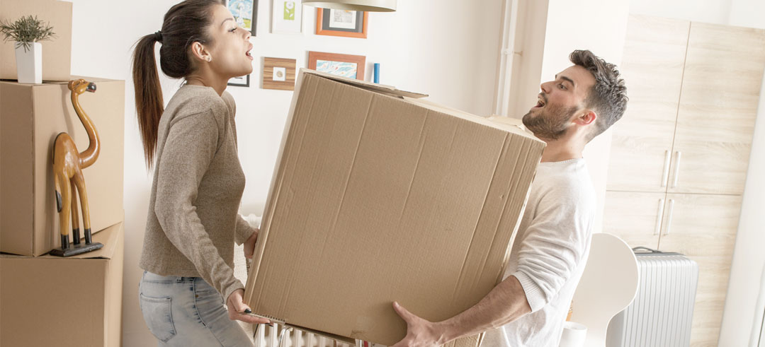 Pareja cargando una caja de cartón durante una mudanza