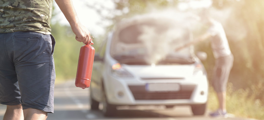 Persona con un extintor ante un coche echando humo